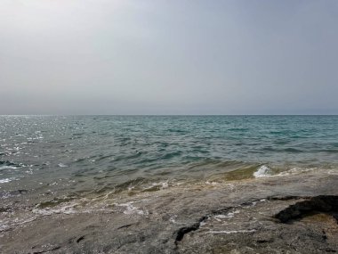 Uçsuz bucaksız gökyüzünün altında Issyk-Kul 'un kayalık kıyısı ve berrak suyu.