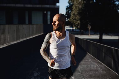 Sakallı, dışarıda koşan, şehirde kardiyo eğitimi alan atletik bir adamın portresi.