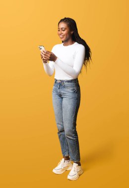 Akıllı telefondan internet sitelerinde gezinen çekici, çok ırklı genç bir kadın sosyal ağlarda sohbet eden, mobil uygulama kullanan, arkadaşlarıyla mesajlaşan, haberleri paylaşan, sarıda izole edilmiş...