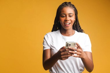 Akıllı telefon kullanan eğlenceli bir kadın, ekrana şaşırmış ve gülümsüyor, bir kadın beklenmedik bir şekilde hoş bir anlaşma ya da bilgilendirme alıyor, telefona bakıyor ağzı açık, izole edilmiş