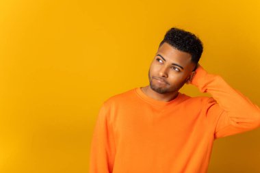 Kafası karışmış, 20 'li yaşlarda genç, düşünceli bir Hintli. Şüpheleniyor, elini başının üstüne koyuyor. Sorunları nasıl çözeceğini bilmiyor, sarı arka planda izole edilmiş.