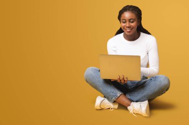 Modern woman using laptop computer isolated on yellow. Portrait of multiracial female using online technology for doing business, computer app for accounting