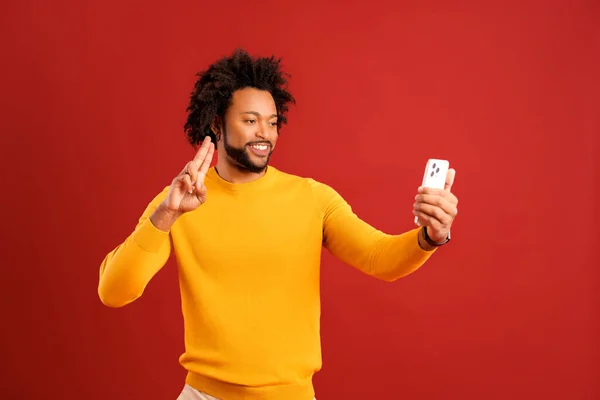 若いアフリカ系アメリカ人のハンサムな男の自撮り カメラを見て手をジェスチャー 自分自身を記録巻き男の肖像画 屋内撮影所は赤の背景に隔離された — ストック写真