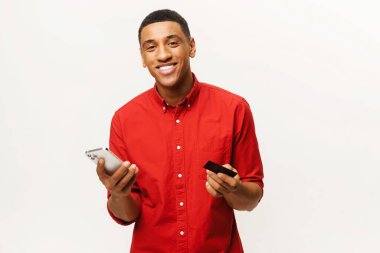 Orta Doğulu mutlu adam internetten alışveriş yapıyor. Uzun zamandır beklenen cep telefonunun parasını erkekler ödüyor. Adam internetten alışveriş yapmak için akıllı telefon ve kredi kartı kullanıyor.