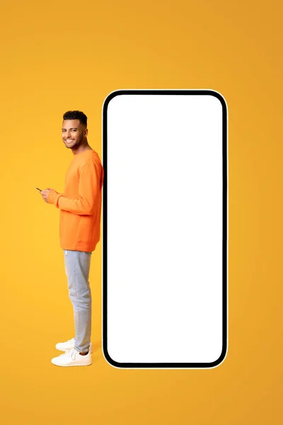 Χαμογελώντας Ελκυστικός Τύπος Στέκεται Κοντά Τεράστιο Smartphone Άδεια Λευκή Οθόνη — Φωτογραφία Αρχείου