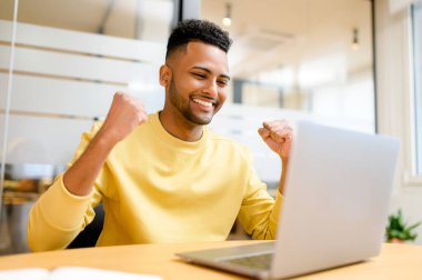 Heyecanlı Pakistanlı iş adamı dizüstü bilgisayara bakıyor ve seviniyor. Beklenmedik bir fırsatla eğlenen, gülümseyen Hintli adam iş teklifi aldı.