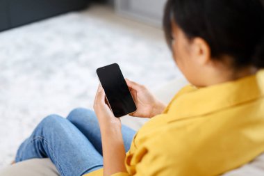 Arkaya bak, elinde akıllı telefon olan boş ekranlı bir kadın, koltukta oturan ve elinde boş ekranlı bir cihaz tutan bir kadın, model, uygulama reklamcısı.