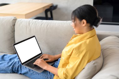 İçerde çalışmak için dizüstü bilgisayar kullanan çok ırklı genç kadının arka görüntüsü. Metin eklemek için boş beyaz laptop ekranı. Teknoloji konsepti