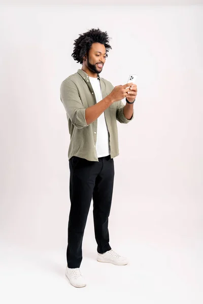 一个快乐的黑人年轻人用白色背景的手机发短信的画像 快乐的非洲裔美国人使用智能手机 喜欢网上聊天 在社交网络上发短信 — 图库照片