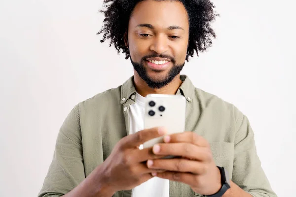 白い背景の上に携帯電話にメッセージを送信陽気な若い黒人男性の肖像画 スマートフォンを使用して幸せなアフリカ系アメリカ人男性 オンラインチャットを楽しんで ソーシャルネットワークでのメッセージ — ストック写真