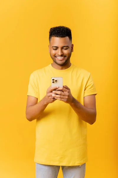 20多岁的印度年轻人穿着休闲装 在黄色背景下使用智能手机拍照 触摸手机屏幕是提高工作效率的必要工具 这些照片在网上能找到灵感 — 图库照片