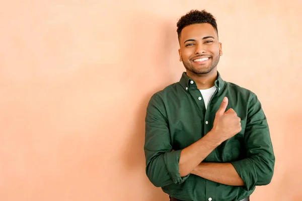 stock image Indian male entrepreneur in casual shirt showing thumb up isolated on orange, businessman looking at the camera and smiles, demonstrating approving, agreement, arab student showing ok gesture