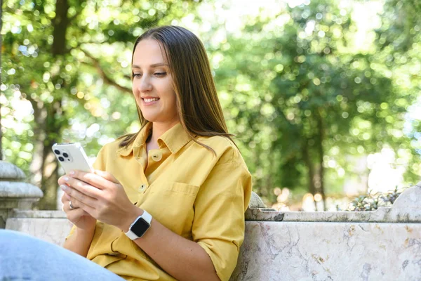Усміхнена Позитивна Молода Жінка Жовтій Повсякденній Сорочці Використовуючи Телефон Відкритому — стокове фото