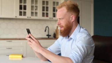 Serene gülümseyen genç kızıl saçlı adam elinde akıllı bir telefonla, e-postaları kontrol ediyor, sosyal ağlarda vakit geçiriyor, mesajlaşıyor ve internette sohbet ediyor. Yan görünüm