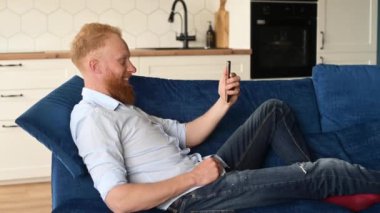 Neşeli kızıl sakallı adam akıllı telefondan arama yapıyor. Arkadaşlarını ya da meslektaşlarını selamlıyor. İnternette toplantı yapıyor.