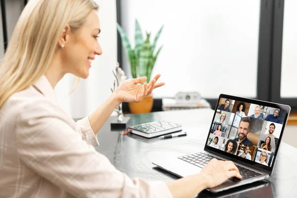 与许多人在线视频讨论在一起 年轻女子坐在笔记本电脑前 有许多图标 屏幕上的人的照片简介 视频会议应用程序 带有翻转图的办公室 — 图库照片