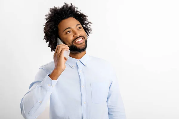 白いシャツを着たアフリカ系アメリカ人の男性が携帯電話で話し 白い背景に孤立した楽しい会話 スタジオの肖像画 — ストック写真