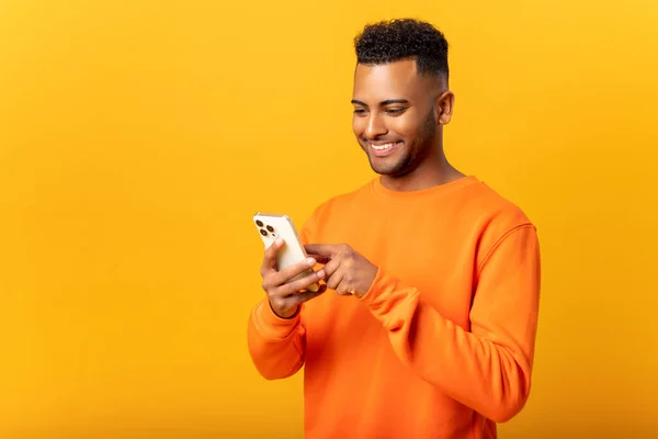 Ecstatic Young Indian Man Standing Isolated Yellow Using Trendy Smartphone — Photo