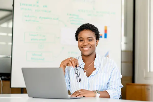 若いカリスマ性の若いアフリカ系アメリカ人女性オフィスの従業員の肖像画 ノートパソコンで机に座っている短いヘアカット ポジティブなモチベーションの同僚 — ストック写真