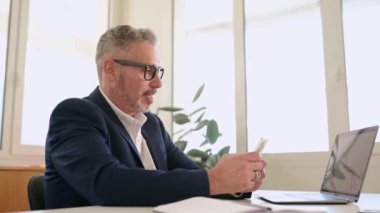 Akıllı telefon, çağdaş orta yaşlı patron, CEO, rahatlamış atmosferdeki e-postaları kontrol eden, kaydıran, borsayı kontrol eden 50 'li yılların akıllı iş adamı ve gözlüklü