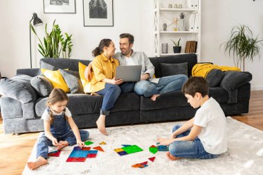 İki ebeveyn rahat oturma odasındaki kanepede dizüstü bilgisayar kullanarak film seyrederken, iki çocuk yerde inşaatçıyla oynarken, kardeş birlikte oyun oynuyorlardı. Evde dört kişilik bir aile.