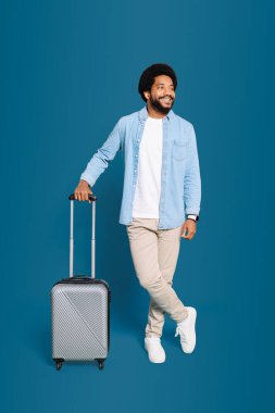 A Brazilian man with a playful expression standing with his suitcase conveys the excitement and anticipation of a new travel experience. This image captures the spirit of a lighthearted journey clipart