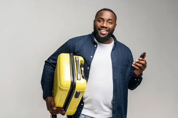 Usmívající Afroameričan Kufrem Smartphonem Ruce Ztělesňuje Pohodu Vzrušení Moderního Cestování — Stock fotografie