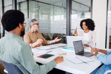 Meslektaşlar, bir ofiste olgun bir adam, lider ya da akıl hocası ile canlı bir fikir alışverişinde bulunurlar. Gözlüklerle bir noktaya dikkat çekerler. İşbirlikçi ve iç açıcı bir iş tartışmasını somutlaştırırlar..