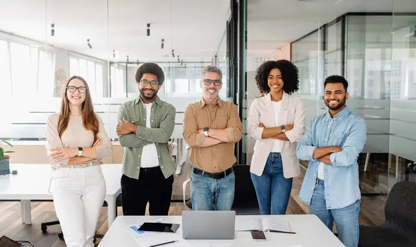 5人の同僚の多様なグループは オフィスに自信を持って立っています 腕は笑顔で交差し 共同作業環境でビジネス上の課題に取り組む準備ができている団結し 協力チームを象徴しています — ストック写真