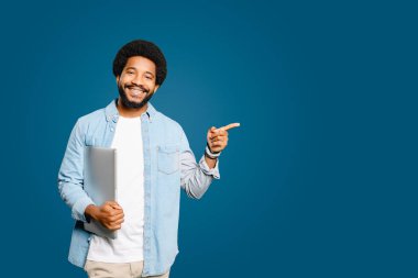 Maviye izole edilmiş dizüstü bilgisayarı olan yakışıklı, iyimser bir Brezilyalı. Erkek bir çalışan, öğrenci ya da serbest çalışan bir reklamcı, içerik için boş alana dikkat ediyor