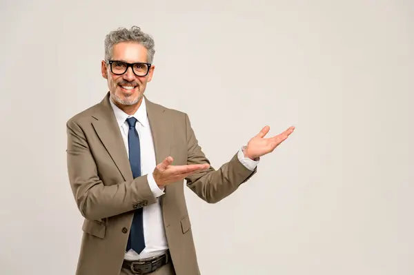 stock image Senior businessman pointing openly with both hands as if presenting new ideas or a concept, illustrating openness and readiness to innovate in the corporate environment. Advertising concept, copyspace