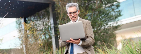Seasoned Businessman Glasses Suit Works Attentively His Laptop While Standing — Stock Photo, Image