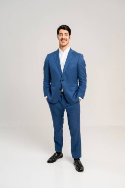 Çekici gülüşü ve doğrudan göz teması projesiyle genç işadamı, müşteri karşılama rolleri ve kişisel bağlantıyı vurgulayan hizmetler için ideal bir dostane ve misafirperver tavır sergiliyor..