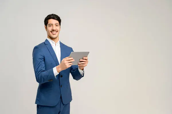 青いスーツの男は自信を持ってタブレットを使用しています 彼の笑顔を伝える技術との容易さと専門知識 ビジネスコミュニケーションの概念 デジタルソリューション テクノロジーを促進したビジネス管理 — ストック写真