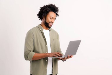 Dizüstü bilgisayar kullanan, beyaz, erkek girişimci, serbest çalışan, kıvırcık saçlı, günlük kıyafetlerini giyen ve e-postalarını kontrol eden özgüvenli, Afro-Amerikan bir adam.