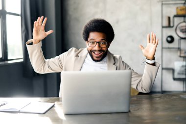 Modern ofis ortamındaki neşeli Brezilyalı işadamı sürpriz ya da heyecanı ifade eder. Ellerini kaldırarak ani bir farkındalık ya da başarılı bir sonuç alabileceğini gösterir.