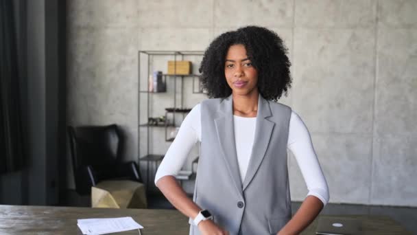 一位年轻而专业的非洲裔美国女性在办公桌前散发出自信 她的双臂交叉 面带微笑 她的穿着完美地平衡了正式和随意的办公室装束 — 图库视频影像