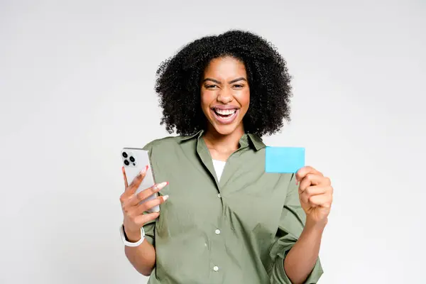 アフリカ系アメリカ人の女性は 彼女のスマートフォンとクレジットカードで祝い おそらく賞品を獲得した後 またはオンラインで大いに得た後で祝います — ストック写真