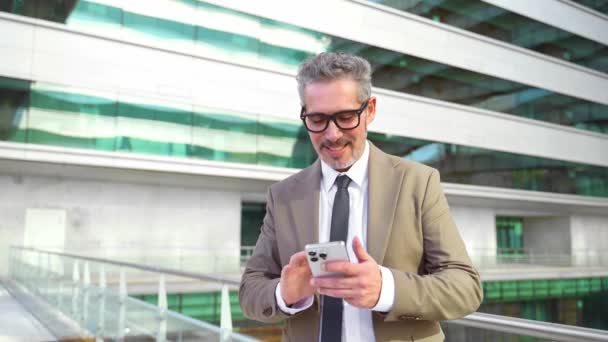 Empresário Sênior Inteligente Sorrindo Enquanto Olha Para Seu Smartphone Revisando — Vídeo de Stock