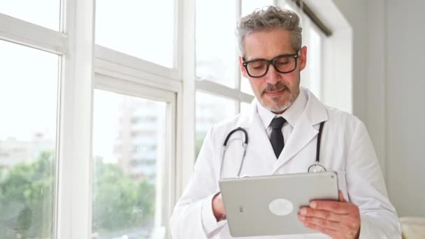 Médico Sênior Com Óculos Comportamento Amigável Segura Tablet Junto Uma — Vídeo de Stock