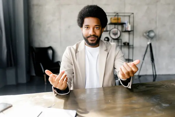 stock image Brazilian businessman gestures invitingly during a presentation, engaging with an unseen online audience, his modern office setting lending a professional ambiance to the interaction. Virtual meeting