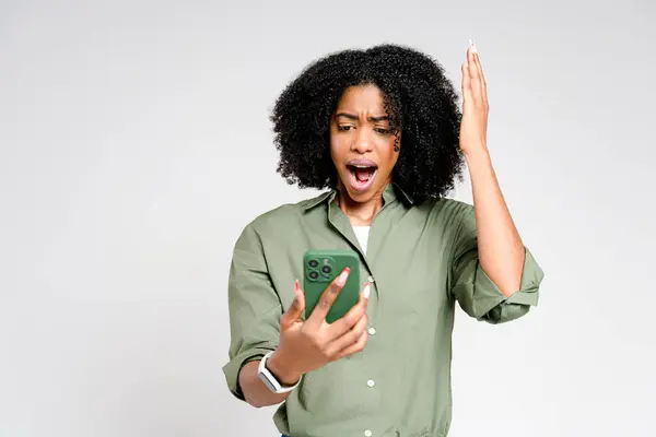 当这个非洲裔美国女人看着她的智能手机 她的表情充满了惊讶和欢乐 这让她感到震惊和幽默 — 图库照片