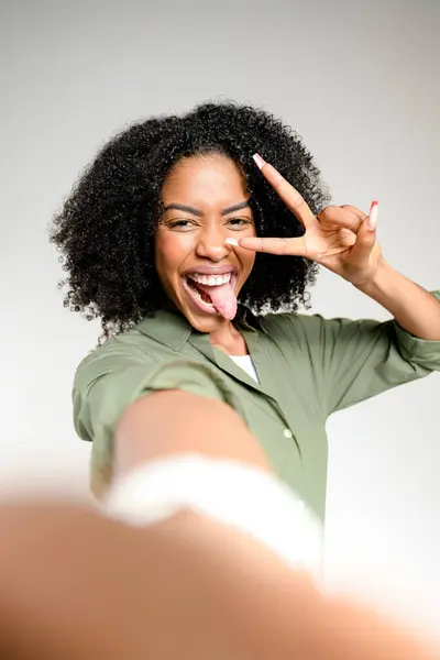 Afroameričanka Kudrnatými Vlasy Dává Znamení Míru Vystrkuje Jazyk Hravé Selfie — Stock fotografie