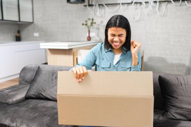 Coşkulu, çok ırklı genç bir kız çevrimiçi teslimat emri aldı. Çekici kadın oturma odasındaki kutuyu açarken seviniyor.