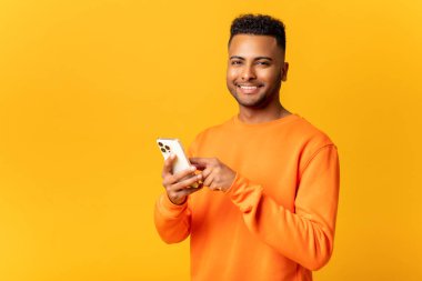 İyimser Hintli adam gündelik kıyafetler giyiyor. Akıllı telefondan mesaj atıyor. Mesajlaşıyor, gülümsüyor.