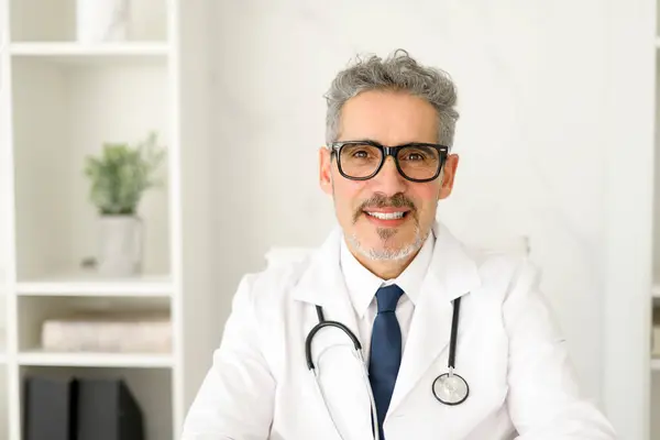 Doświadczony Lekarz Siwych Włosach Okularach Pozuje Profesjonalnego Portretu Siedzącego Nowoczesnym — Zdjęcie stockowe