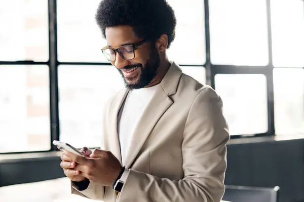 stock image The young businessman is smiling as he looks at his phone, a symbol of a successful entrepreneur staying connected, the backdrop of a bright, airy office. Male office employee using phone indoors