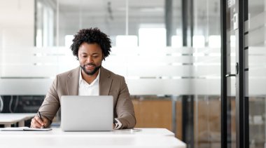 Bir toplantıda ya da görevlerini organize ederken notlar yazan Afro-Amerikalı işadamı, profesyonel bir ortamda konsantrasyon ve ayrıntılara dikkat çekiyor.