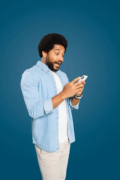 Joven Asombrado Usando Teléfono Expresando Sorpresa Emoción Parado Aislado Azul — Foto de Stock