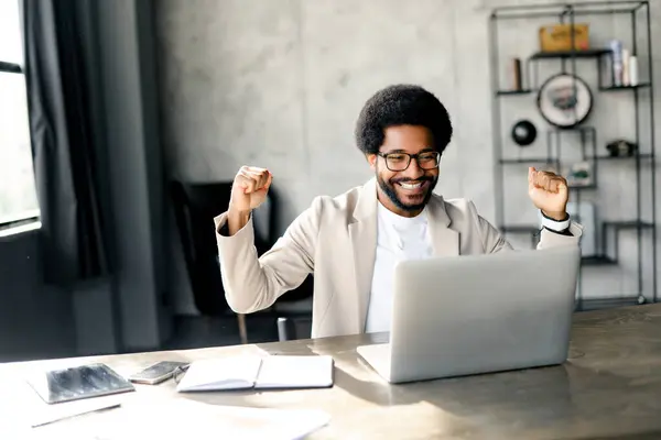ブラジルの実業家は 純粋な喜びの表情でノートパソコンの前に手を投げ 現代の職場での成功の瞬間を意味し よくやった仕事のスリルを象徴しています — ストック写真